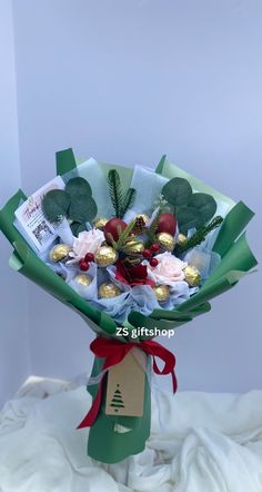 a bouquet of flowers and chocolates wrapped in green paper on a white sheeted surface