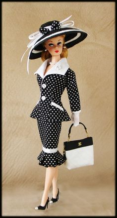 a doll is dressed in black and white polka dots with a handbag on her shoulder