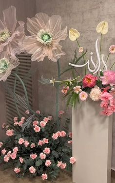 a vase filled with pink and white flowers on top of a table next to a plant