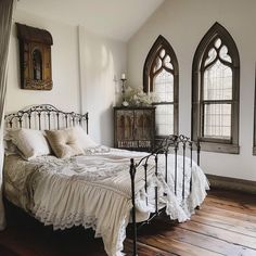 a bed sitting in a bedroom next to two windows