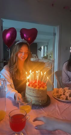 a woman sitting in front of a cake with lit candles