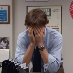 a man sitting at a desk with his hands on his face while covering his eyes