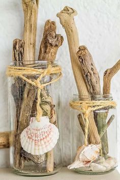 two glass jars filled with driftwood and seashells