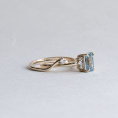 an engagement ring with a blue topazte and two diamonds on the side, sitting on a white surface