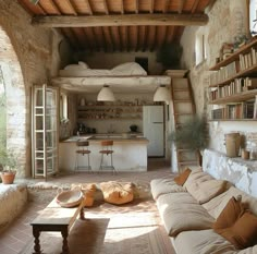 a living room filled with furniture next to a kitchen and dining area in an old stone building