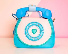 a blue and white purse sitting on top of a pink table next to a wall