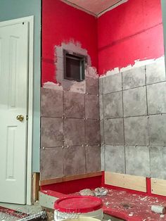 the bathroom is being remodeled with red and gray paint on the walls, and white doors