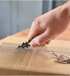 a person is holding a pair of scissors in front of a box with some key chains on it