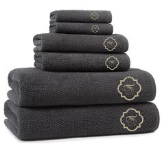 five towels stacked on top of each other in black and gold embroidered with an image of a lion