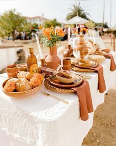 a table set up with plates, bowls and utensils for an outdoor dinner