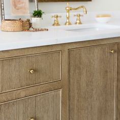 a bathroom vanity with two sinks and gold faucets