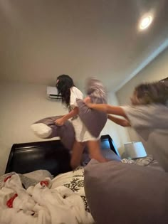 two girls jumping on a bed in a room