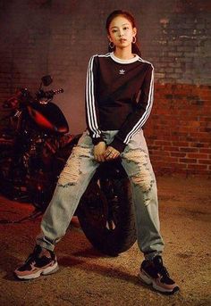 a woman sitting on top of a motorcycle in front of a brick wall with her legs crossed