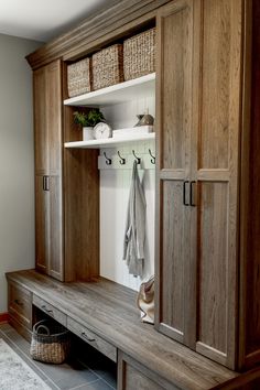 a wooden bench sitting under a window next to a wall mounted coat rack with baskets on it