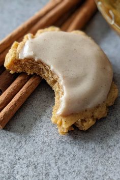 cinnamon cookies with icing and cinnamon sticks next to them on a gray countertop