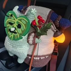 a crocheted bag with an animal decoration on it's back pocket, sitting in the passenger seat of a car