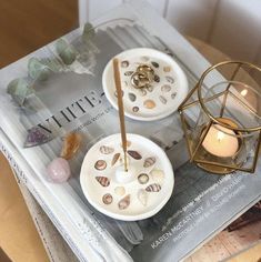 two plates with seashells and candles on top of a magazine