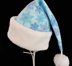 "NEW  This festive Santa hat is made up in a cozy blue and lavender snowflake patterned flannel cotton fabric. The hat is trimmed with a snowy white soft Sherpa faux fur turn up brim. Proportions of the hat are generous and will fit most head sizes, ladies or gents.    The styling is a slouch cone, traditional Santa stocking cap. Measurement for opening for your head is 24-25\" circumference and the length is 19\".  There is a snowy white faux fur pompom dangle. If you need more than the number Christmas Party Adult, Blue Santa Hat, Blue And Lavender, Holiday Hats, Santa Stocking, Stocking Cap, Blue Flannel, White Faux Fur, Costume Hats