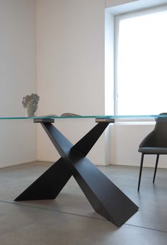 a glass table with an artistic design on it in front of a window and two chairs