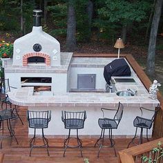 an outdoor kitchen with grill and bar stools