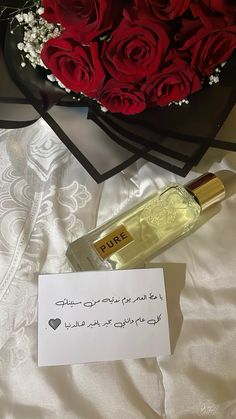 a bottle of perfume sitting on top of a table next to a bouquet of roses