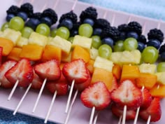 fruit skewers with grapes, strawberries, and blueberries on them are ready to be eaten