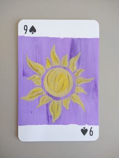 a purple and yellow playing card with the sun painted on it