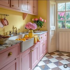 a kitchen with yellow walls and pink cabinets, white counter tops and checkered flooring