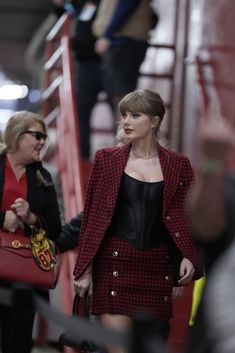 the woman is walking down the stairs with her hand on her hip and carrying a red purse