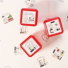 three red magnets sitting on top of a white table covered in stamps and stickers