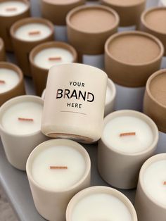 many candles are arranged on a table with the words your brand here printed on them