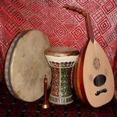 two musical instruments sitting on top of a red and white cloth covered floor next to each other