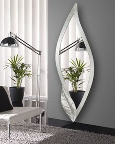 a mirror hanging on the wall next to a chair and potted plant in front of it