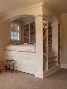 a bedroom with built in bookshelves and stairs leading up to the bed area