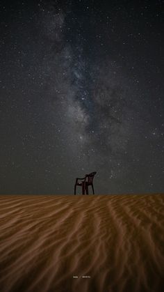 a chair sitting on top of a sandy field under the stars