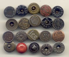 an assortment of different metal buttons on a white surface with words and symbols in the middle