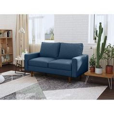 a living room with a blue couch and potted plants on the side table in front of it