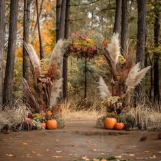 an outdoor wedding arch decorated with fall flowers and pamodia plants in the woods