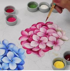 someone is painting flowers with watercolors on the table