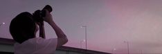 a woman is holding up her camera to take a picture with the sky in the background