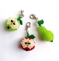 three beaded christmas ornaments hanging from hooks on a white surface, one is green and the other is red