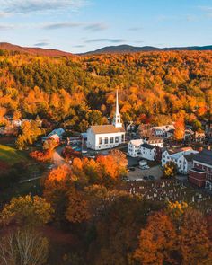 an aerial view of a small town surrounded by trees in the fall with colorful foliage