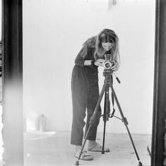 a woman standing in front of a camera on a tripod looking into the distance