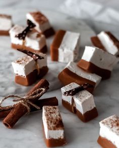 marshmallows and chocolate are arranged on a marble surface with twine ribbons