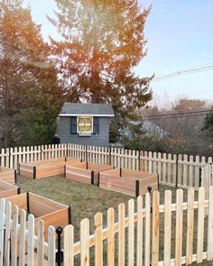 a fenced in area with several raised wooden planters and a shed on the other side