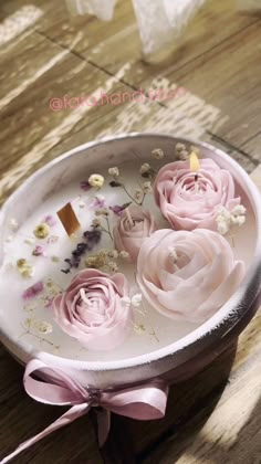 some pink flowers in a white bowl on a table