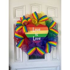 a rainbow heart shaped wreath with the words love is love written on it in front of a white door