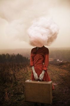 a woman in a red dress sitting on top of a suitcase covered in cotton floss