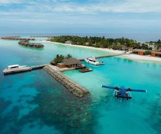 an airplane flying over the ocean near a small island with houses on it and boats in the water