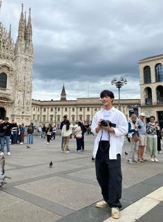 a man standing in front of a large building with lots of people around him looking at his cell phone